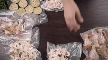 Kadın eli, dondurmak için farklı sebzelerle vakum torbaları ve et alıyor. Yiyecek deposu. Üst Manzara. Yakın plan.