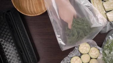 Yeşil dereotu için vakum ambalaj makinesi kullanan bir kadın. en üstteki görünüm