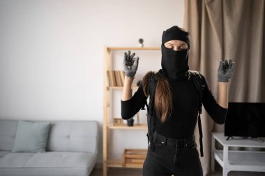 Hırsız, hırsız ve hırsız. Siyah kar maskesi takan ve eldiven takan genç bir kadın yoga jestinde elini yayıyor. Rahatlayıp birinin evine meditasyon yapıyor. Boşluğu kopyala