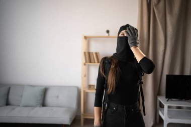 Hırsız, hırsız ve hırsız. Siyah kar maskesi takan stresli genç bir kadın ve birinin evine duygu yüklü eldivenler. Boşluğu kopyala