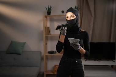 Hırsızlık ve soygun kavramı. Siyah kar maskeli kadın hırsız ya da soyguncu elinde para tutan sesli mesajı dikte ediyor. Boşluğu kopyala