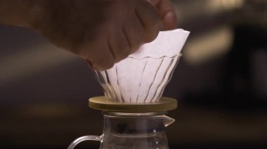 Kahveci huniye kağıt kahve filtresi koyuyor, yakın plan. Drip filtre kahve demleme işlemi. Boşluğu kopyala
