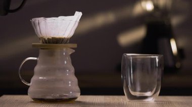 Kahve bardağının üzerine çaydanlıktan sıcak su döküyor. Sabah kahvesi mutfakta damlıyor. Boşluğu kopyala