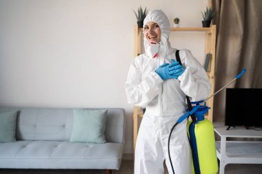 Haşere Kontrol Servisi 'nden kadın ilaçlamacı evin içinde çalışıyor, sprey şişesiyle kalbi tutarken minnettar görünüyor ve evde teşekkür ediyor. Boşluğu kopyala