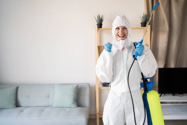 Haşere Kontrol Servisi 'nden kadın ilaçlamacı evde yumruklarıyla kutlama yapan sprey şişesiyle çalışıyor. Boşluğu kopyala