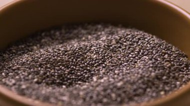 Tahta kaseden kaşıkla kepçelenmiş chia tohumları, vegan gıda konsepti, sağlıklı beslenme ve lif proteini ve omega besin değeri yüksek süper yiyecekler.