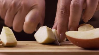 Dişi ellerin taze elmaları küçük parçalara ayırması ahşap kesme tahtasıyla keskin bıçakla, yemek hazırlama, yemek pişirme, beslenme ve sağlıklı yaşam tarzıyla.