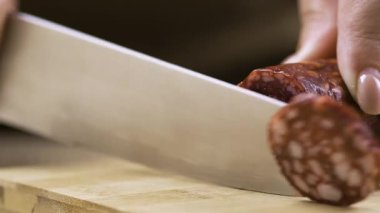 Aşçının yakın çekimi füme sosisi büyük bir bıçakla keser. Yemek pişirme konsepti