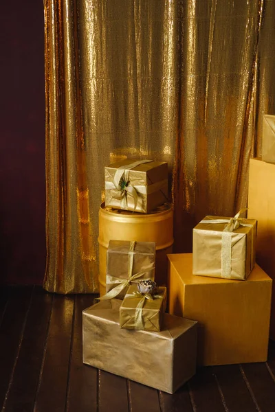 五彩缤纷的礼物堆放在金黄色的包装纸上 用亮晶晶的金光闪闪的背景装饰着彩带 图库照片