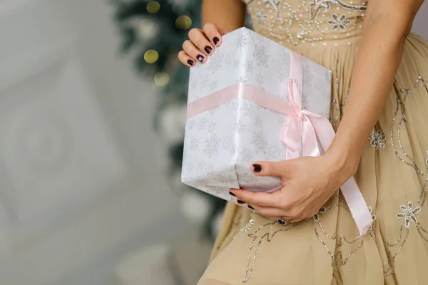 白い背景にピンクリボンで美しいクリスマスプレゼントを保持している女性の手の閉鎖ショット — ストック写真