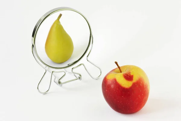 stock image Red apple looking in the mirror and seeing itself as a pear - Concept of dysmorphobia and distorted self-image