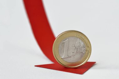 Euro coin on red decreasing arrow - Concept of decrease in euro value and loss of money clipart