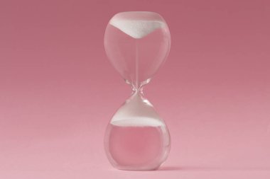 Upside-down hourglass on pink background - Concept of reverse time clipart