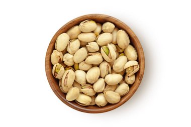 Beyaz arka planda tahta kasede fıstıklar.