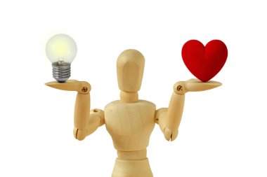 Ampul ve kalbi beyaz arka planda dengede olan tahta manken kalp ve akıl kavramı arasındaki denge