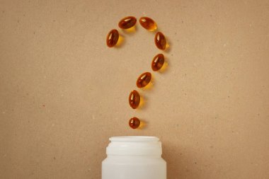 Omega 3 balık yağı kapsüllerinden yapılmış soru işareti geri dönüşümlü kağıt arka planda - takviye kavramı, vitaminler ve sağlıklı yeme yaşam tarzı