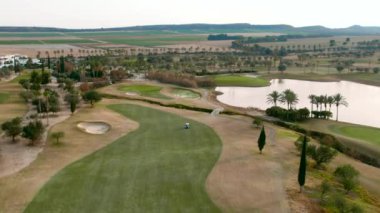 Tipik İspanyol golf sahaları ve evleri. Golf sporu için yeşil çimenler, palmiye ağaçları ve göller. Yeşil alan, tropikal iklim, hava aracı bakış açısı. Alicante vilayeti. Costa Blanca 'da. İspanya