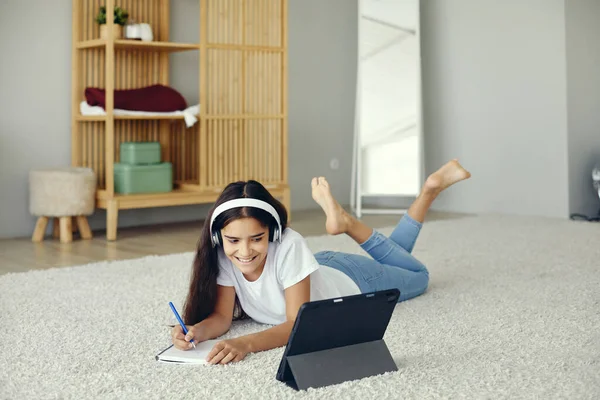 かなり前の10代の12代の女の子は 床に横たわって 無線ヘッドフォンを着用オーディオコースの勉強を聞く 家庭教育用デジタルタブレットを使用しています Eラーニング ジェンZのための現代的な技術の使用新しいスキルを獲得 — ストック写真