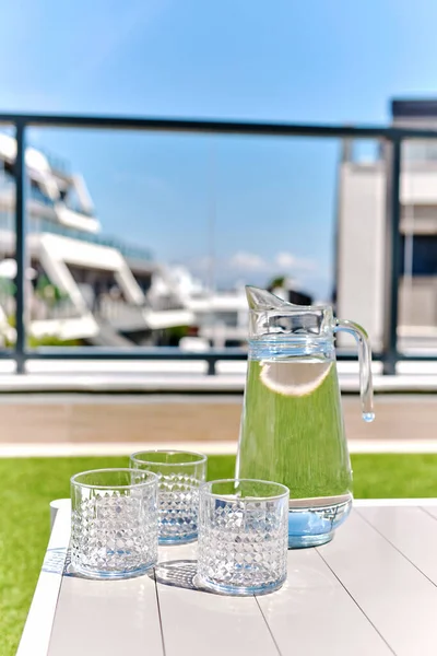 在夏天的露台上 用新鲜的天然水和空的干净玻璃杯把罐子关上 没有人 夏季小食 健康的生活方式 防止脱水的概念 — 图库照片