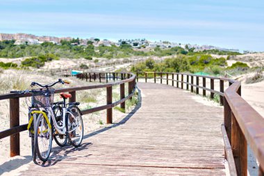 Tahta boş tahta üzerinde iki bisiklet kum tepeciklerinden Akdeniz 'e ve kumlu plajlara gidiyor, insan yok. Costa Blanca, Avrupa, İspanya. Espana. Seyahat ve turizm kavramı