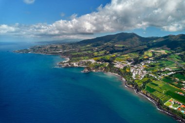 Havadan çekim, insansız hava aracı bakış açısı, Azores 'in resimli doğası. Yeşil tepeler ve bulutlu gökyüzü, güneşli yaz günlerinde Atlantik Okyanusu manzarası. Sao Miguel, Ponta Delgada adası. Portekiz