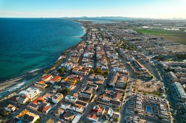Torre de la Horada plajı, yukarıdan manzara. Güneşli bir günde deniz kenarına insansız hava aracı ve konut evleri çatıları. Costa Blanca, Alicante, İspanya. Seyahat ve tatiller