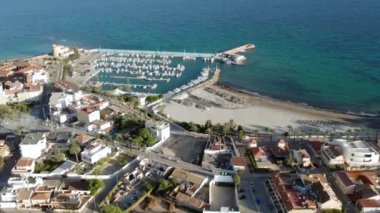 Torre de la Horada kumsalı, yukarıdan manzara. Güneşli bir günde limana bakan insansız hava araçları, demirli yatlar ve kayıkhanelerin çatılarına bakan evler. Costa Blanca, Alicante, İspanya. Seyahat kavramı