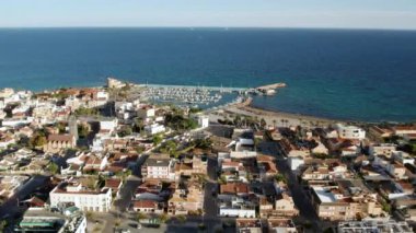 Torre de la Horada kumsalı, yukarıdan manzara. Güneşli bir günde limana bakan insansız hava araçları, demirli yatlar ve kayıkhanelerin çatılarına bakan evler. Costa Blanca, Alicante, İspanya. Seyahat kavramı