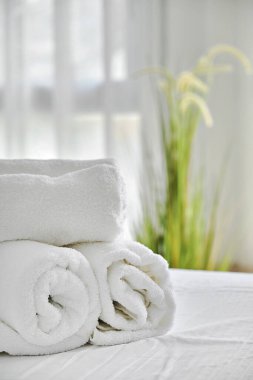 Yatak odasındaki rahat yatakta üç beyaz havlu, manzarayı kapat. Konaklama, tatil ve hijyen kavramı