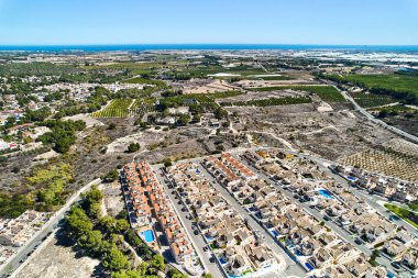 Drone point of view countryside meadows and Pinar de Campoverde residential district view with modern new-built houses, villas view from above. Summer day. Costa Blanca, Province of Alicante, Spai clipart