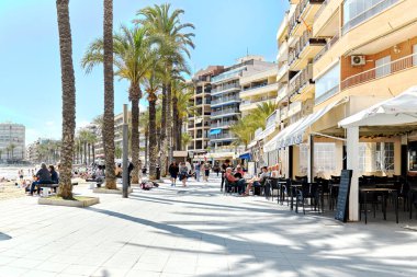 Torrevieja, İspanya - 19 Nisan 2024: Torrevieja şehri kıyı şeridi. Del Cura sahilinin yakınındaki gezinti alanında bir sürü insan var. Costa Blanca, Alicante, İspanya. Seyahat yeri ve turistik yerler