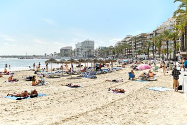 Torrevieja, İspanya - 19 Nisan 2024: Torrevieja şehrinin kumsal sahili. Del Cura 'da güneşlenen bir sürü insan var. Costa Blanca, Alicante, İspanya. Seyahat yeri ve turistik yerler