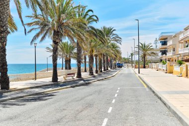 Torre de la Horada 'nın manzaralı deniz manzaralı palmiye ağaçları. Boş yaya geçidi ve turkuaz Akdeniz 'i var. Costa Blanca, İspanya. Yaz tatili, seyahat ve tatil kavramı