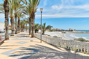 Torre de la Horada 'nın manzaralı deniz manzaralı palmiye ağaçları. Boş yaya geçidi ve turkuaz Akdeniz 'i var. Costa Blanca, İspanya. Yaz tatili, seyahat ve tatil kavramı
