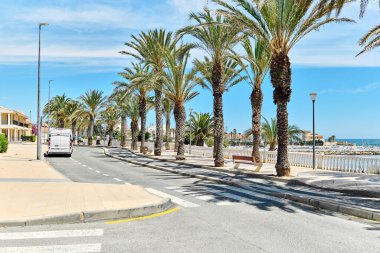 Torre de la Horada 'nın manzaralı deniz manzaralı palmiye ağaçları. Boş yaya geçidi ve turkuaz Akdeniz 'i var. Costa Blanca, İspanya. Yaz tatili, seyahat ve tatil kavramı