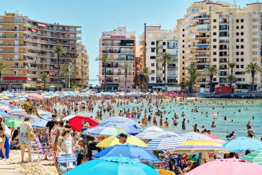 Torrevieja, İspanya - 23 Haziran 2024: Torrevieja tatil ve rahatlama kavramı, güneşli bir yaz günü, Playa del Cura plajında güneşlenen bir sürü insan. Costa Blanca, İspanya, Alicante ili