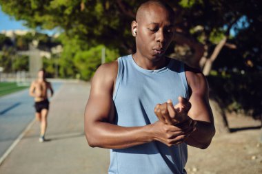 Ciddi bir koşucu dışarıda duruyor ve vücut çalışmasından sonra kalp atışlarını ve nabzını parmaklarıyla kontrol ediyor. Sağlık, spor konsepti
