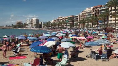 Torrevieja, İspanya - 2 Ekim 2024: Akdeniz kıyısındaki kumlu sahilde dinlenen insanlar. Seyahat yerleri kavramı. Costa Blanca, İspanya
