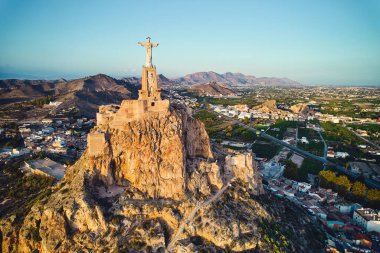 Engebeli tepenin tepesindeki Monteagudo heykeli, gün batımına bakan şehir manzarası. Antik kale ve çevreleyen manzara. Kültür ve tarihi sembol. Murcia, Alicante ili. İspanya