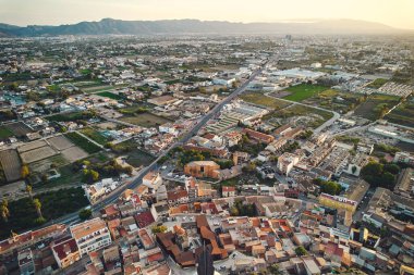 Monteagudo 'nun insansız hava aracı görüntüsü, Murcia, İspanya yakınlarındaki banliyö bölgesi. Kentsel ve kırsal manzaranın panoramik manzarası, tarım arazisi, evler, yollar, ve altın akşam ışığı altında uzak dağlar. İspanya