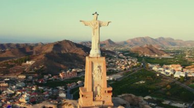 Engebeli tepenin tepesindeki Monteagudo heykeli, gün batımına bakan şehir manzarası. Antik kale ve çevreleyen manzara. Kültür ve tarihi sembol. Murcia, Alicante ili. İspanya