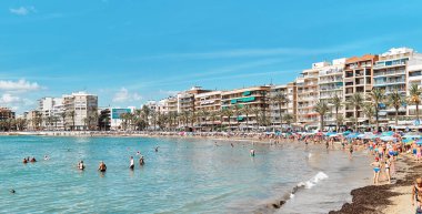 Torrevieja, İspanya - 28 Eylül 2024: Güneşli bir sonbahar gününde insanlar Playa Del Cura plajında güneşleniyor. Seyahat yerleri kavramı. Torrevieja, Alicante ili, Costa Blanca, İspanya