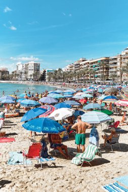 Torrevieja, İspanya - 28 Eylül 2024: Güneşli bir sonbahar gününde insanlar Playa Del Cura plajında güneşleniyor. Seyahat yerleri kavramı. Torrevieja, Alicante ili, Costa Blanca, İspanya