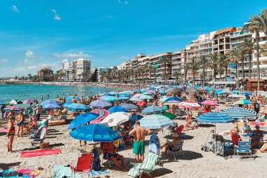 Torrevieja, İspanya - 28 Eylül 2024: Güneşli bir sonbahar gününde insanlar Playa Del Cura plajında güneşleniyor. Seyahat yerleri kavramı. Torrevieja, Alicante ili, Costa Blanca, İspanya