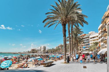 Torrevieja, İspanya - 28 Eylül 2024: Güneşli bir sonbahar gününde insanlar Playa Del Cura plajında güneşleniyor. Seyahat yerleri kavramı. Torrevieja, Alicante ili, Costa Blanca, İspanya