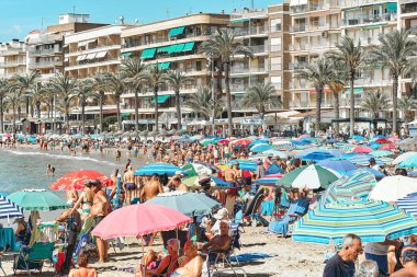 Torrevieja, İspanya - 28 Eylül 2024: Güneşli bir sonbahar gününde insanlar Playa Del Cura plajında güneşleniyor. Seyahat yerleri kavramı. Torrevieja, Alicante ili, Costa Blanca, İspanya