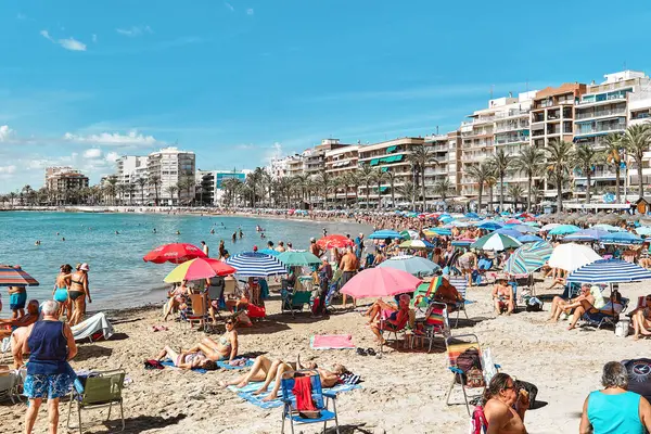 Torrevieja, İspanya - 28 Eylül 2024: Güneşli bir sonbahar gününde insanlar Playa Del Cura plajında güneşleniyor. Seyahat yerleri kavramı. Torrevieja, Alicante ili, Costa Blanca, İspanya