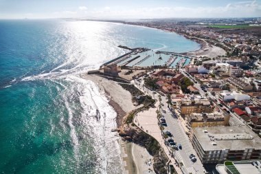 Hava aracı bakış açısı, güneşli bir günde Torre de la Horada kasabası, konut evleri manzarası ve Akdeniz turkuaz suları. Tatil köyü. Alicante ili, İspanya