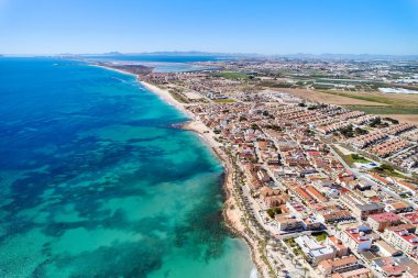İspanya 'nın Torre de la Horada kıyı kasabasının çatıları, Akdeniz' in turkuaz körfezi ve güneşli bir günde kumsal manzaralı sahili. Costa Blanca, Alicante vilayeti. İspanya