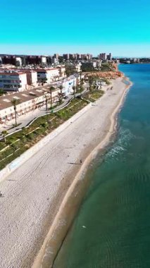 Hava manzaralı Mil Palmeras kıyı şeridi, sahil evleri, gezinti güvertesi, kumlu plaj ve turkuaz Akdeniz açık mavi gökyüzü altında, seyahat, turizm ve emlak için ideal. Costa Blanca, İspanya